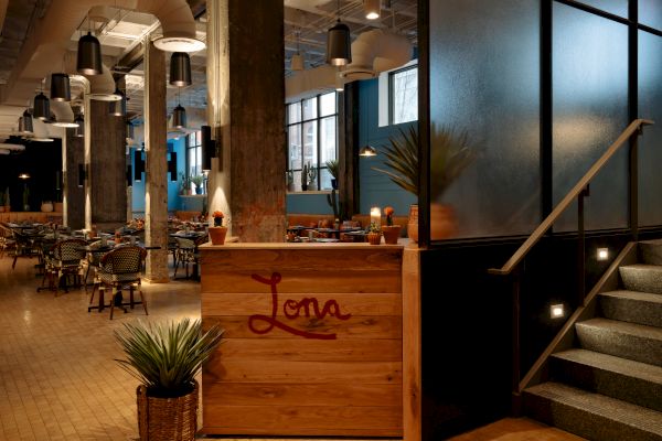 The image shows a modern restaurant interior with a wooden reception desk labeled 