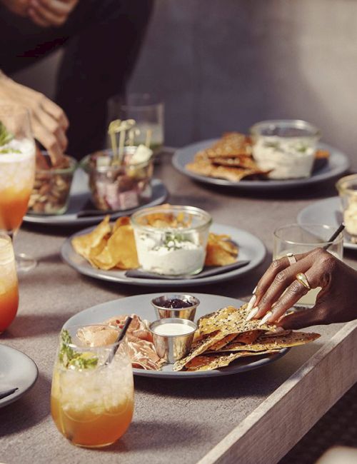 People enjoying a meal with dishes like nachos and drinks on a table.