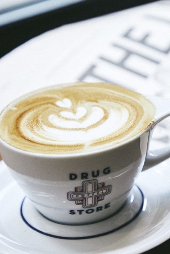 A cup of coffee with latte art sits on a saucer labeled 