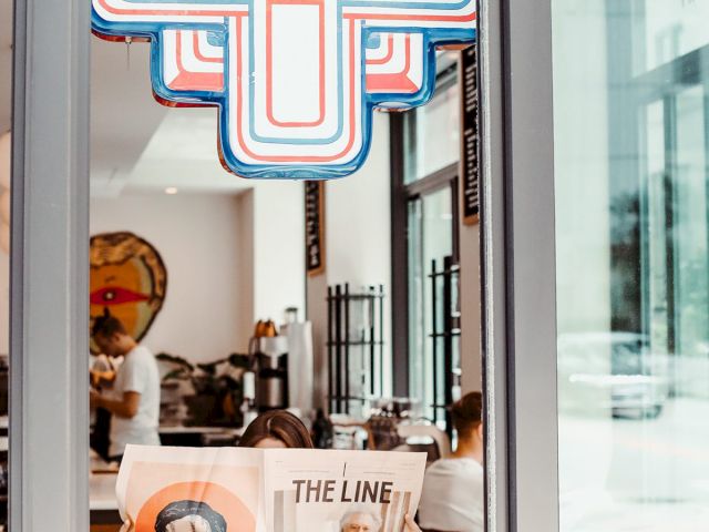 A coffee shop with a retro sign. A person reads 