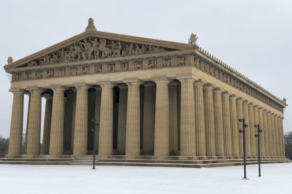 The image shows a replica of the Parthenon, featuring classical Greek architecture with columns and detailed sculptures on the pediment.