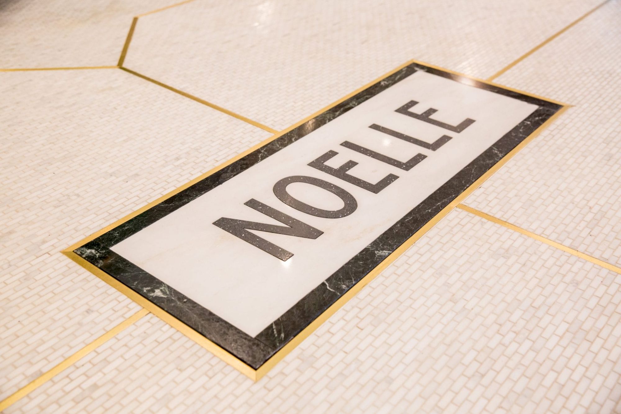 The image shows a tiled floor with the word 