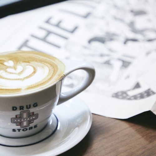 A latte with foam art in a cup labeled 