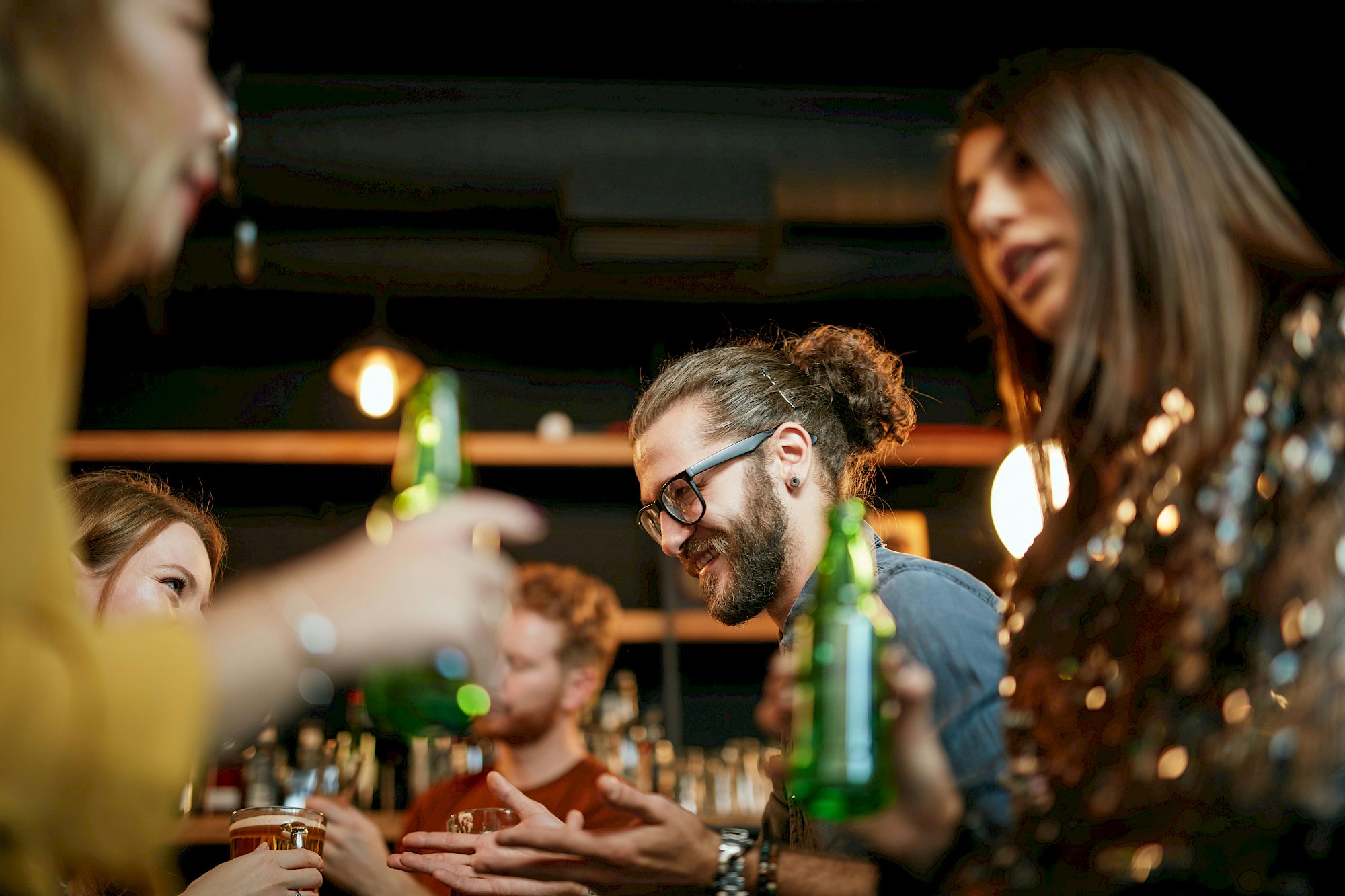 People socializing with drinks in a bar, engaged in conversation and enjoying the lively atmosphere.