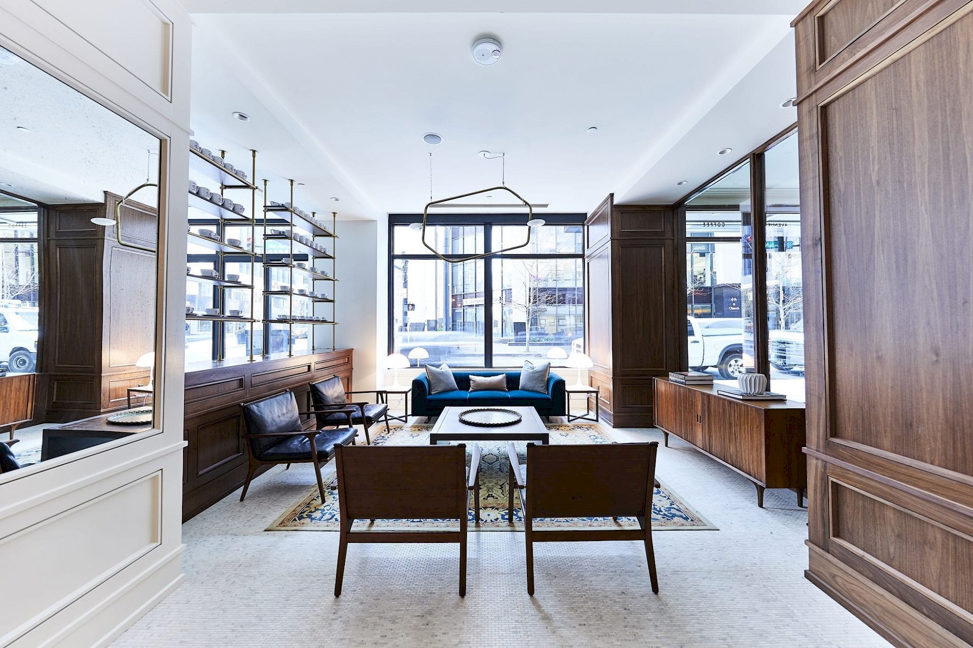 A modern living room with wooden furniture, shelves, a sofa, armchairs, a coffee table, and large windows for natural light.