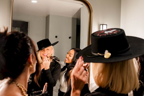 People in a room with a mirror, wearing hats and engaging in conversation or an activity.