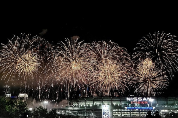 Fireworks explode over Nissan Stadium at night, creating a vibrant display of light and color in the sky above the stadium.