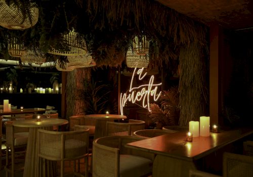 A dimly lit restaurant with wooden tables, wicker chairs, and candles. Neon sign reads 