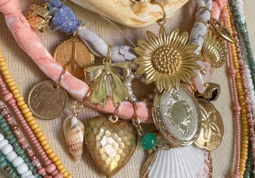 A collection of colorful beaded necklaces with assorted pendants including a sunflower, shell, and heart on display.
