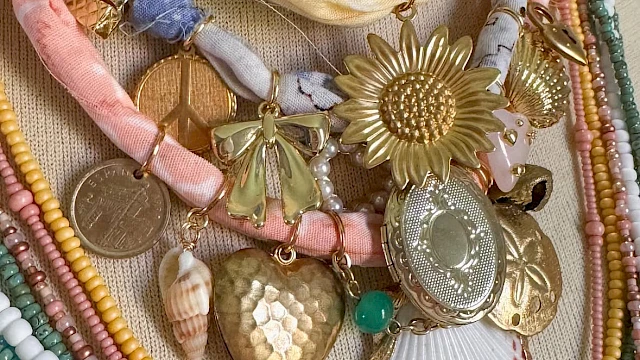 A collection of colorful beaded necklaces with assorted pendants including a sunflower, shell, and heart on display.